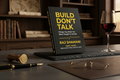 Book titled 'Build Don't Talk' by Raj Shamani on a table with a glass of red wine and other items.